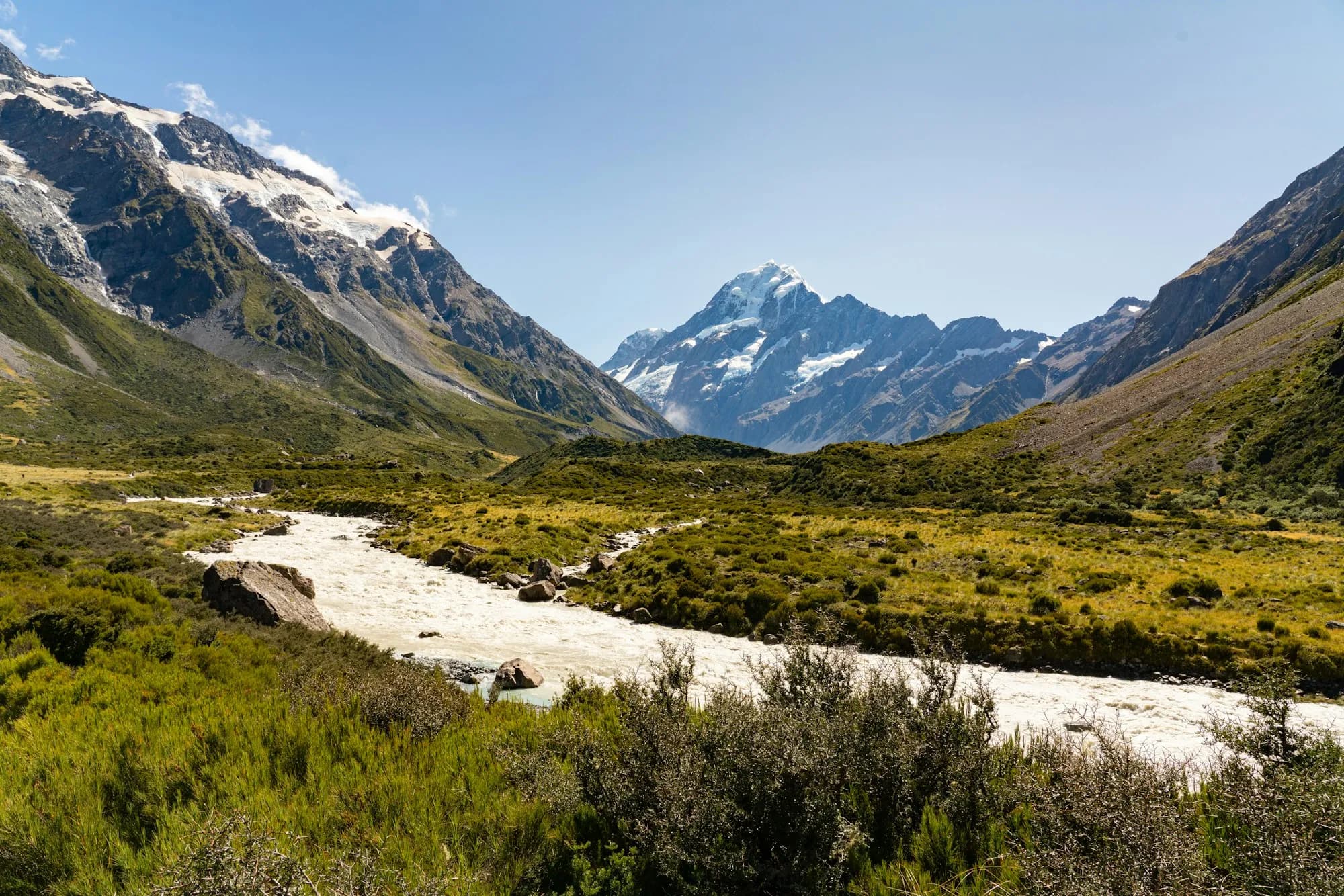 Green grassland below snow-covered mountains at Mount Cook