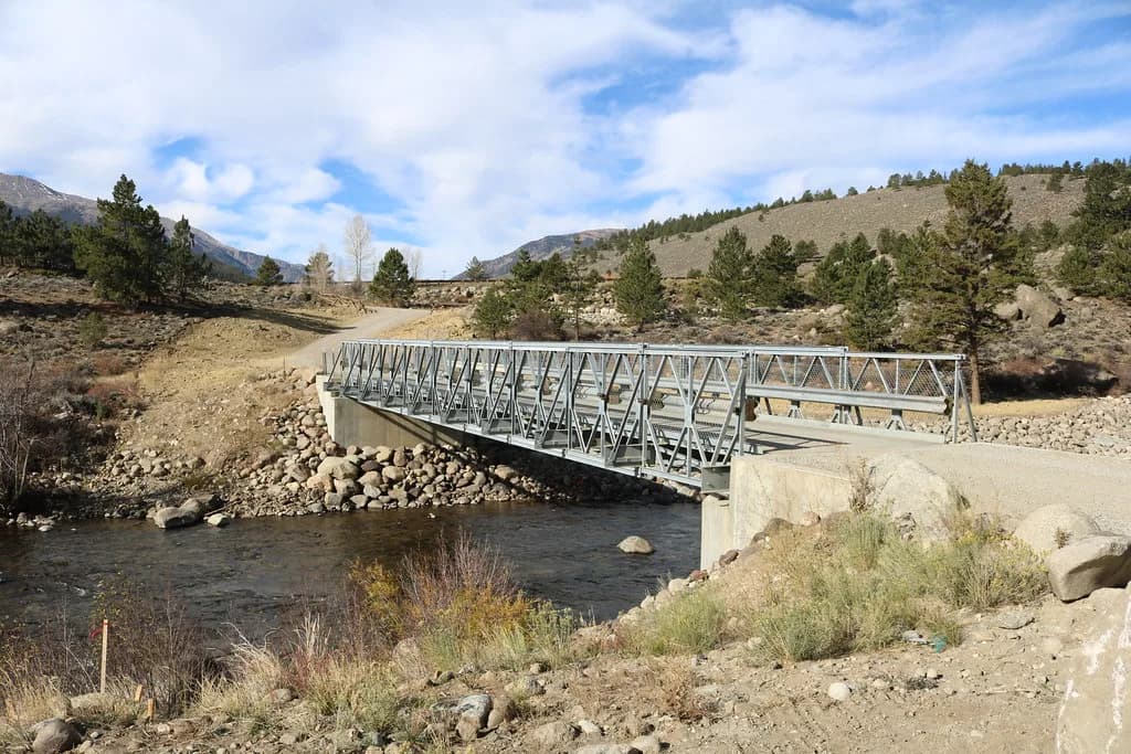 A metal truss bridge spanning the Arkansas River near Granite, Colorado, with mountains and pine trees in the background.