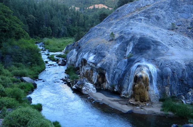 The North Fork Feather River flowing past a large granite outcrop in a forested canyon near Quincy, California.