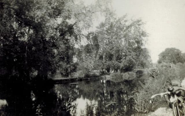 Vintage black-and-white photograph of the River Wylye, with overhanging trees reflected in still water.