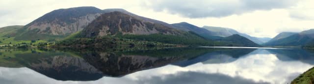 Panoramic view of Ennerdale Water lake with fells reflected in the still water
