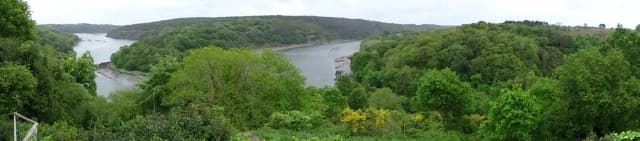 A wide panoramic view of the wooded Trieux river valley with the tidal river visible below.
