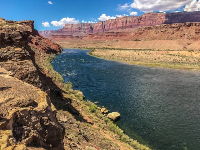 The Colorado River flowing through red-rock Marble Canyon at Lees Ferry, Arizona, with the Vermilion Cliffs rising behind.