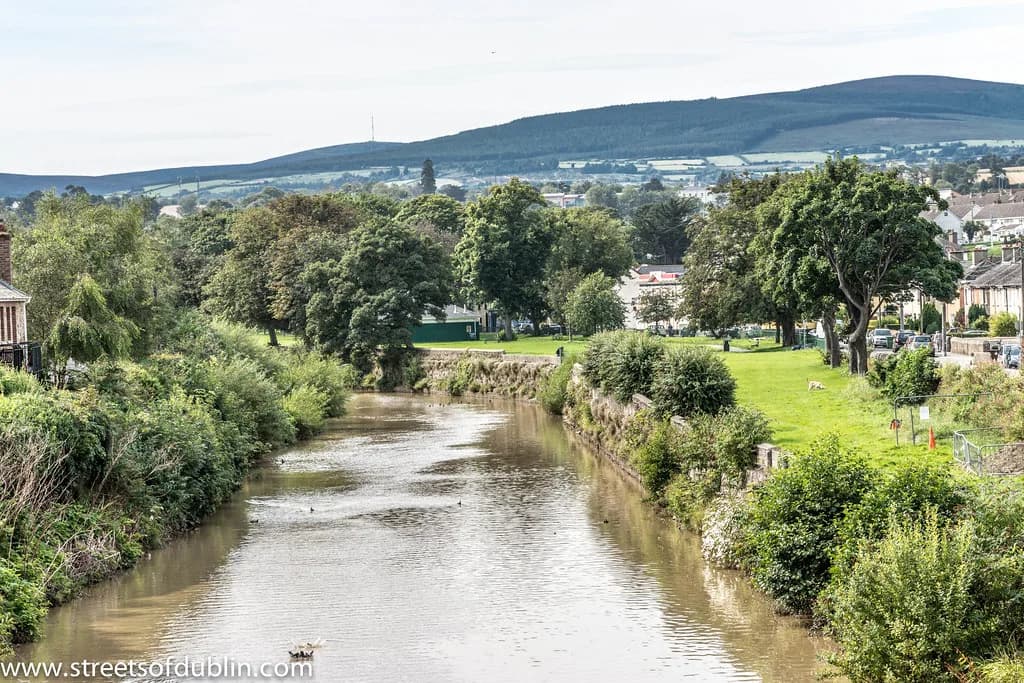The River Dargle flowing through a green park in Bray, County Wicklow, Ireland, with the Wicklow Mountains in the background.
