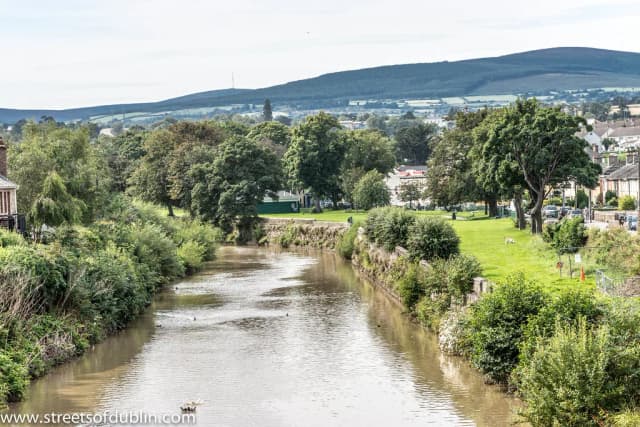 The River Dargle flowing through a green park in Bray, County Wicklow, Ireland, with the Wicklow Mountains in the background.