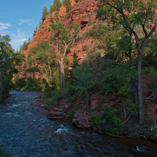 The Fryingpan River flowing through a red sandstone canyon lined with trees near Basalt, Colorado.