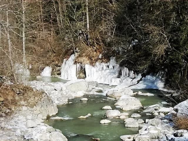 Mountain stream with ice-fringed banks and green pools flowing over boulders near Pont de Beffay on the Borne river, Haute-Savoie