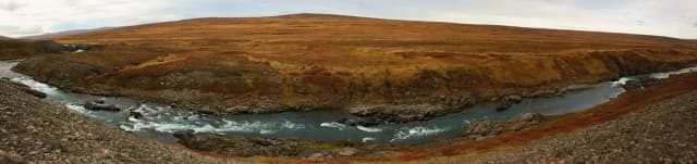 Panoramic view of the Selá river with visible rapids winding through open Icelandic moorland with autumn-coloured vegetation.