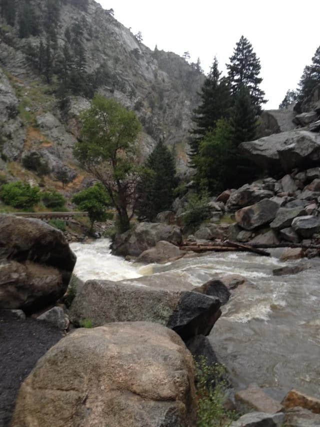 Boulder Creek flowing swiftly through a rocky canyon lined with pine trees and granite boulders in Boulder Canyon, Colorado.