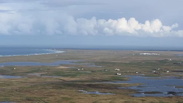A shallow machair loch on South Uist with the sandy grassland machair landscape in the background.