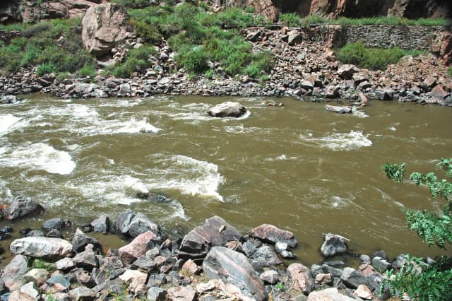 Rocky canyon stretch of the Arkansas River in Royal Gorge, Colorado, with whitewater rapids breaking over boulders.