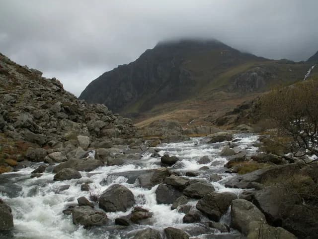 The Ogwen river flowing from Llyn Ogwen with the peak of Tryfan rising behind it.