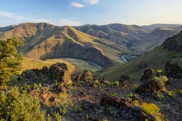 Aerial view of the Deschutes River winding through a golden canyon in central Oregon at sunset.