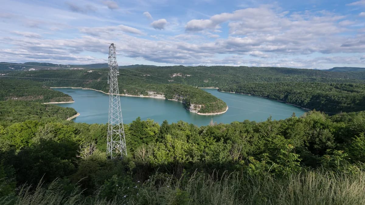 Turquoise waters of Lac de Vouglans winding through forested limestone hills, Jura, France