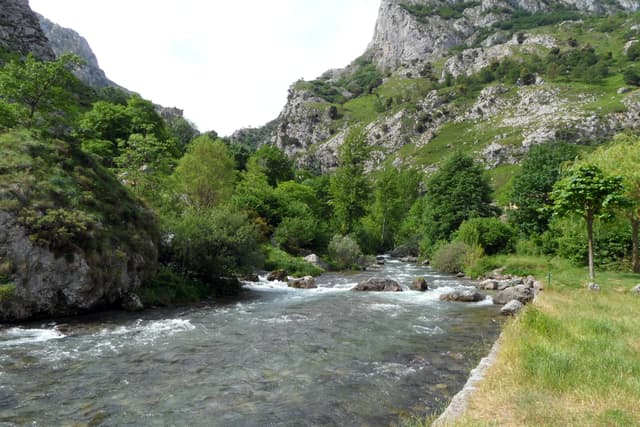 The Río Cares running over boulders and shingle in a wide open valley below Caín de Valdeón.