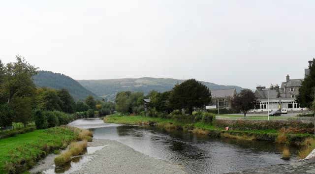 A wide view of the River Conwy at Llanrwst, the broad gravel-bedded channel with wooded valley sides.