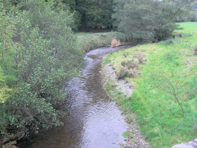 The River Cothi flowing through the village of Pumsaint in Carmarthenshire, tree-lined banks in autumn light.