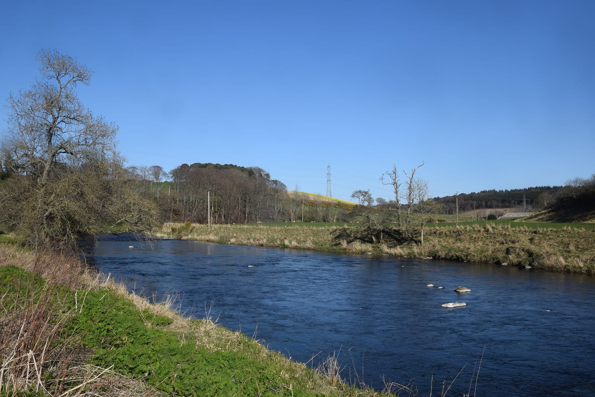 The River Don flowing serenely through agricultural land near Inverurie, Aberdeenshire, in early spring.
