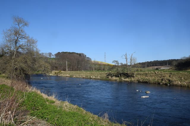 The River Don flowing serenely through agricultural land near Inverurie, Aberdeenshire, in early spring.