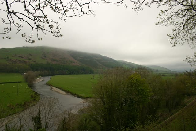 The River Dyfi flowing through the Machynlleth reach with the Cambrian railway line in the landscape.