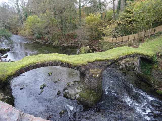 The historic Pont Minllyn packhorse bridge across the River Dyfi at Dinas Mawddwy, water visible beneath the arch.