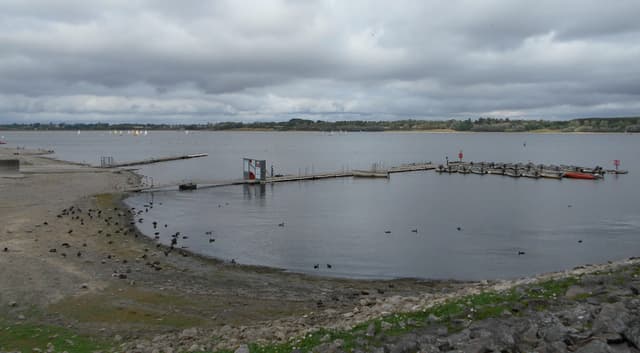 Panoramic view of Draycote Water reservoir from the south-east, the open expanse of water under a blue sky.