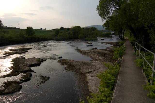 The Ballisodare River flowing over a broad limestone riverbed with a riverside path, Co. Sligo, Ireland