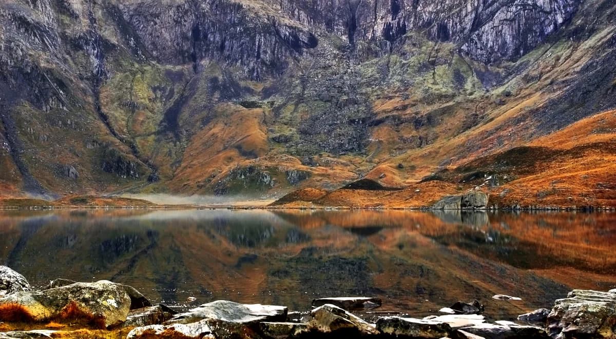 Llyn Idwal, a glacial lake in Cwm Idwal, Snowdonia, with still water reflecting the surrounding mountains.
