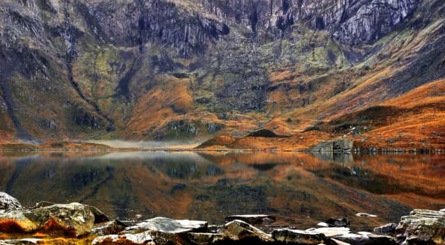 Llyn Idwal, a glacial lake in Cwm Idwal, Snowdonia, with still water reflecting the surrounding mountains.