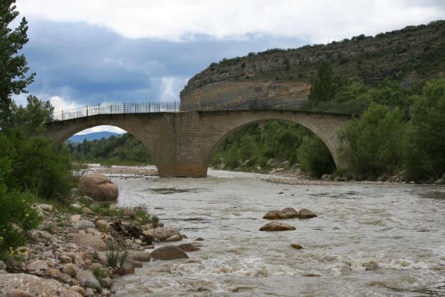Stone arch bridge over the Isábena river with rocky riverbed, Huesca, Aragón