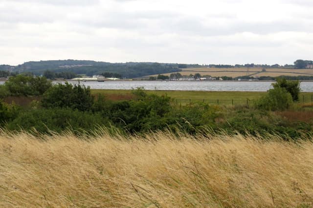 Open water expanse of Farmoor Reservoir viewed from the northern bank with the far shore and sky.