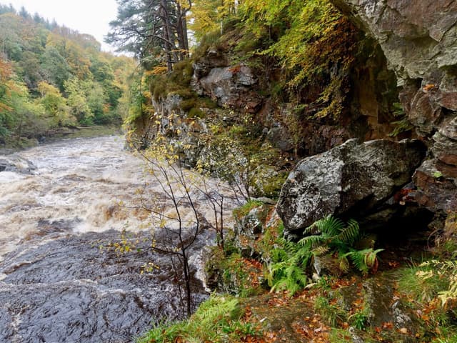 The River Findhorn in full brown spate below Randolph's Leap, water filling the gorge bank to bank.