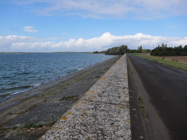 The earthen dam retaining wall at Grafham Water reservoir viewed from the water side.