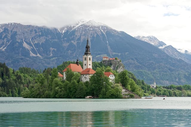 Lake Bled with the island and its church surrounded by open water, Bled Castle on the cliff, Alps behind.