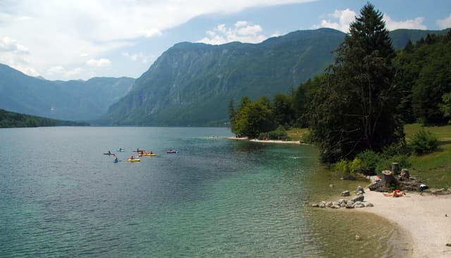 View of Lake Bohinj looking west from the Janez bridge at Ribčev Laz, the open lake and alpine peaks.