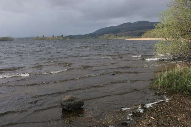 Open water of the Lake of Menteith with the wooded island of Inchmahome in the middle distance.