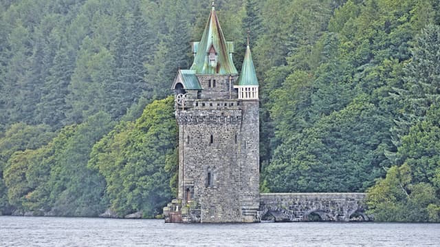 The Victorian Gothic straining tower and approach bridge standing in Lake Vyrnwy, reservoir water surrounding it.
