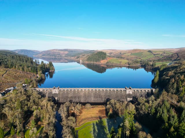 Drone aerial photograph over Lake Vyrnwy reservoir in autumn, the open water ringed by forested hillsides.