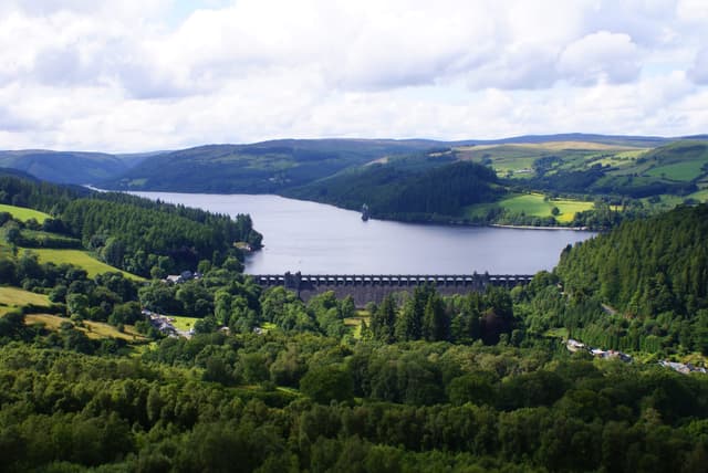 Elevated panoramic view over Lake Vyrnwy showing the dam, the straining tower, and the full length of the reservoir.