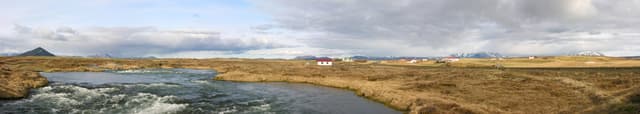 Panoramic view of the Laxá í Aðaldal from the Road 848 bridge, rapids through a broad volcanic landscape.