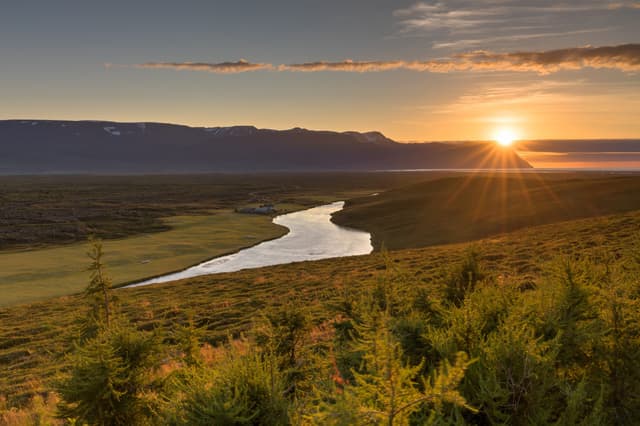 Sunset over the Laxá í Aðaldal floodplain in north Iceland, the broad river valley glowing in evening light.