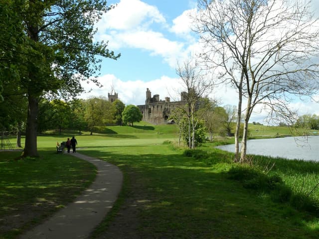 Linlithgow Palace viewed across the loch with open water in the foreground and the palace ruins on the far shore.