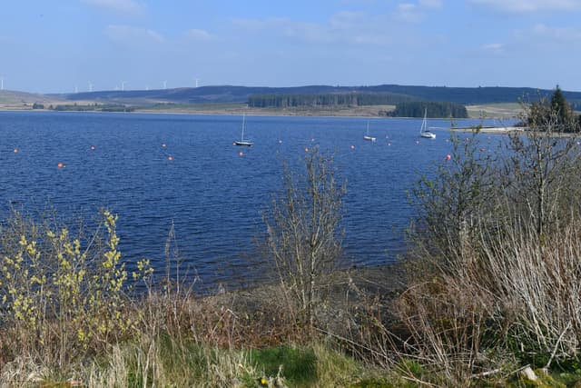 Broad landscape view across Llyn Brenig reservoir on a clear day, moorland hills reflected in calm open water.