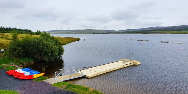 Wide panoramic view of Llyn Brenig reservoir showing the full breadth of open water under a cloudy sky.
