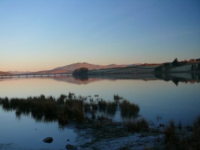 Llyn Trawsfynydd lake shore with open water and moorland backdrop under an overcast Welsh sky.