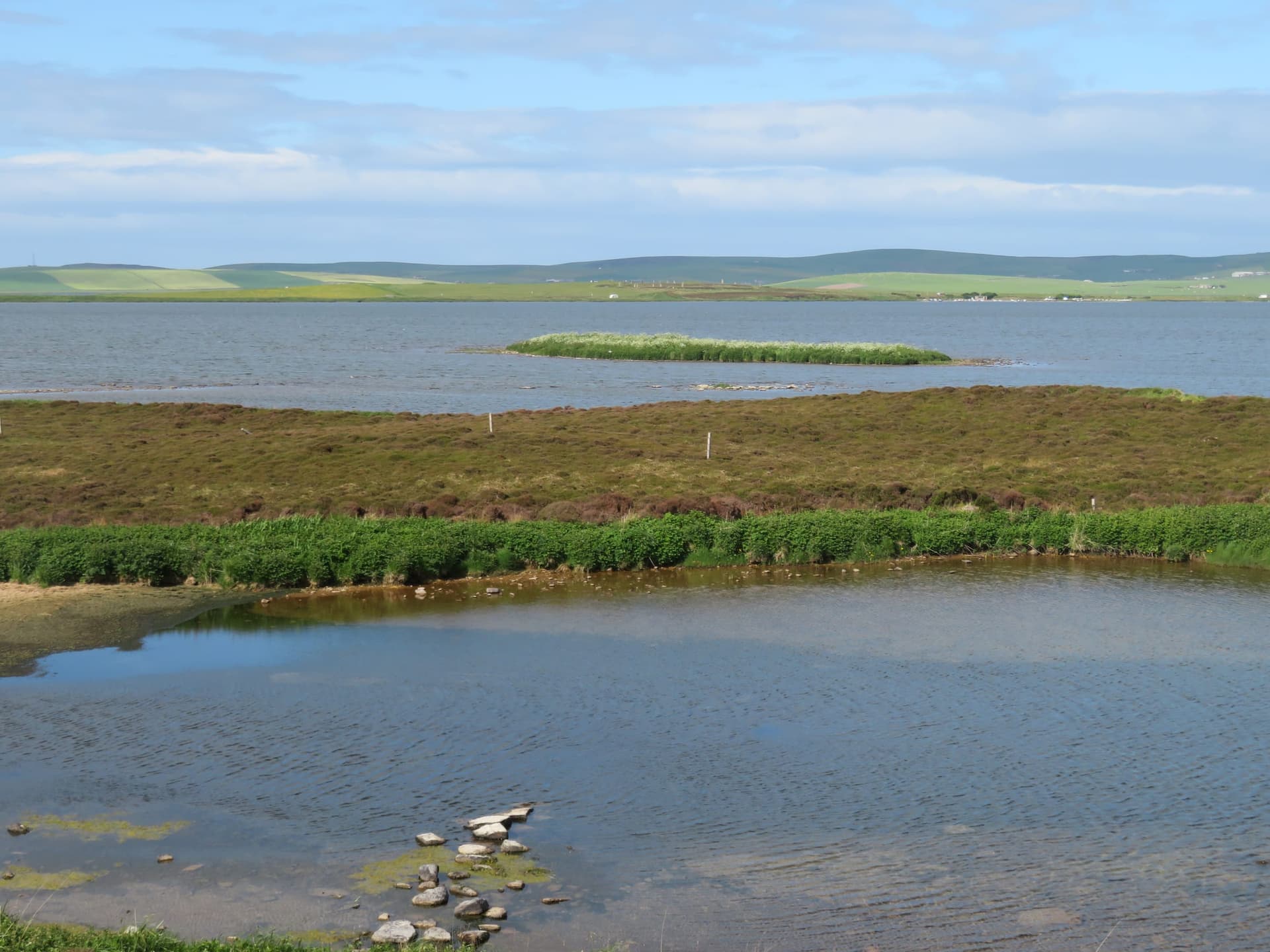 A broad view across the full expanse of Loch of Harray showing the low Orkney shoreline and open sky.