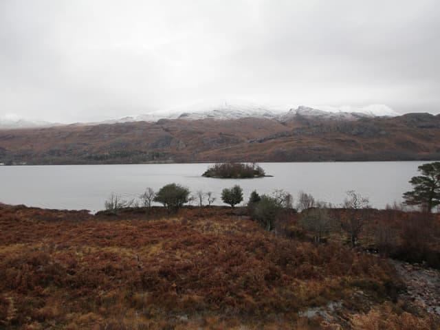 Open water of Loch Maree with the wooded island Eilean Ghrùididh in the middle distance.