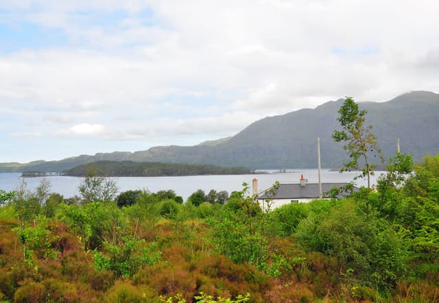 View of Loch Maree from Victoria Falls showing the wooded island Eilean Ruairidh Mòr and the peak of Beinn Àirigh Charr.