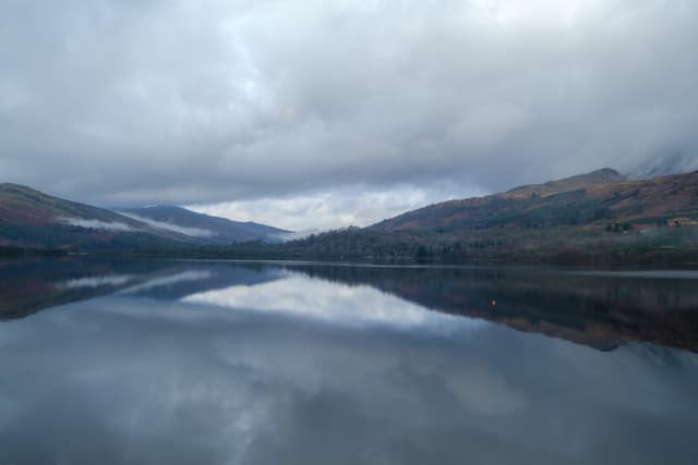 Overcast morning at Loch Tay showing the open loch surface under a heavy grey sky with hills on the far shore.