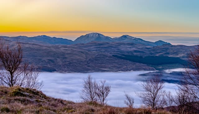 Winter sunrise over Loch Tay with Ben Vorlich and the Ben Lawers massif silhouetted behind the loch in dawn light.